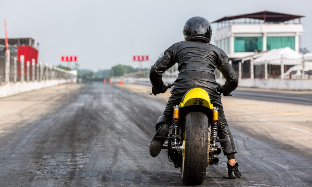 Man on motorbike on the road racing track riding, Biker sitting on motorcycle wearing helmet.