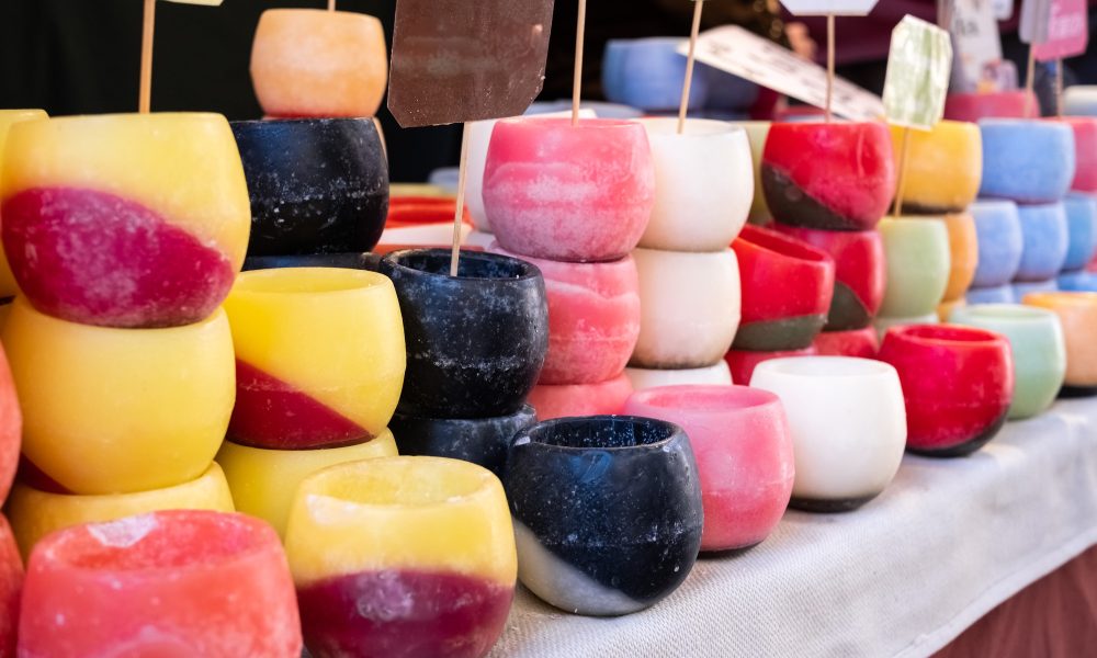 Various wax candles of assorted colors for sale at a craft fair.