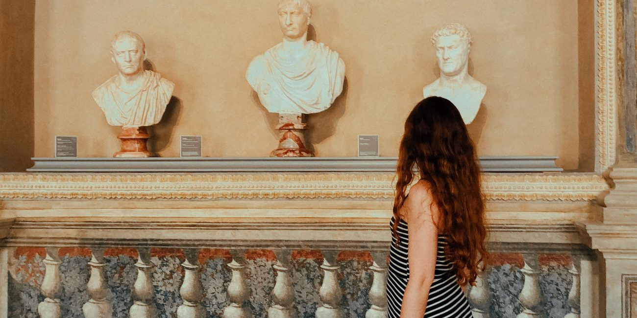 Young woman walking in the museum, sculptures, travel and tourism, travel destinations, from behind