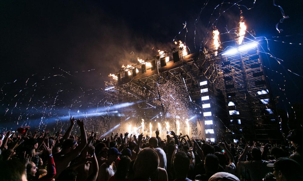 Vibrant concert scene with crowd enjoying night festival and dynamic stage fireworks.