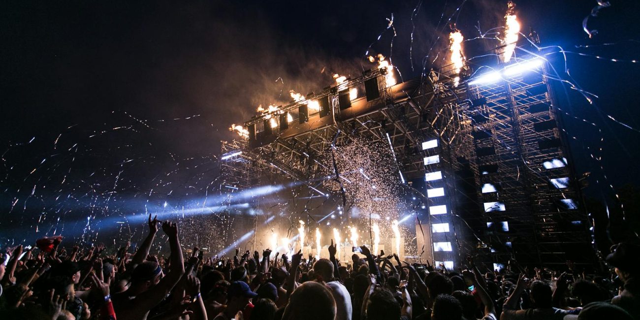 Vibrant concert scene with crowd enjoying night festival and dynamic stage fireworks.