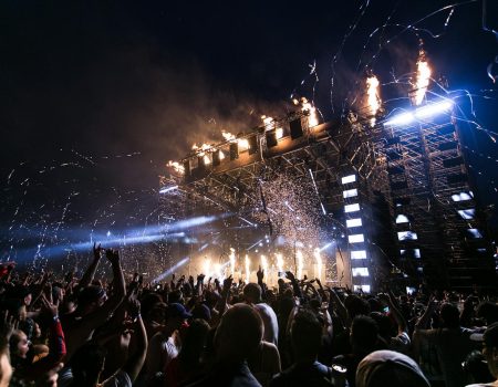 Vibrant concert scene with crowd enjoying night festival and dynamic stage fireworks.