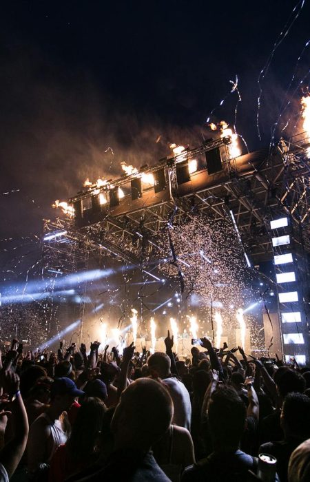 Vibrant concert scene with crowd enjoying night festival and dynamic stage fireworks.