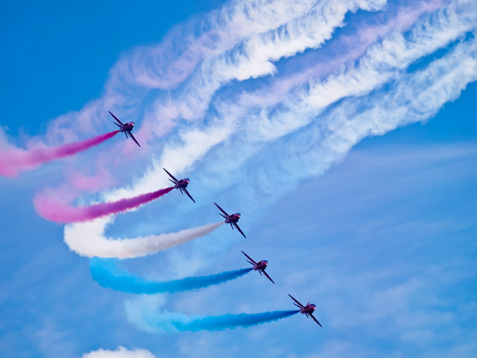 a group of airplanes flying through a blue sky