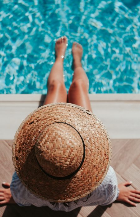 woman sitting on poolside setting both of her feet on pool