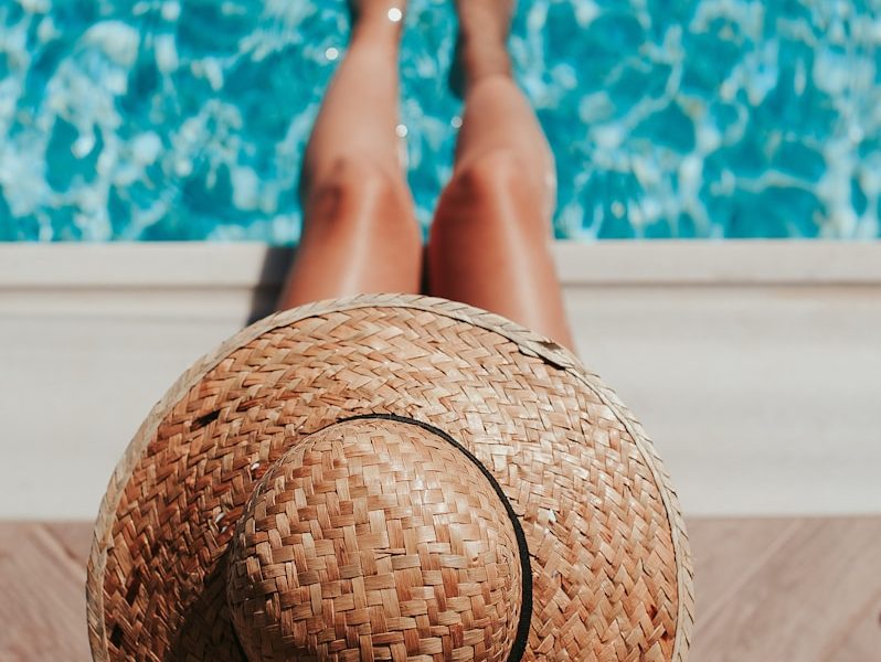 woman sitting on poolside setting both of her feet on pool