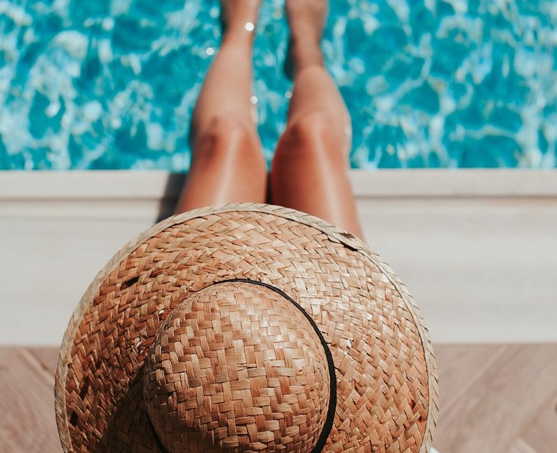 woman sitting on poolside setting both of her feet on pool
