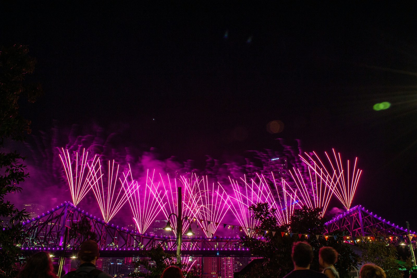 a group of people watching fireworks on a bridge