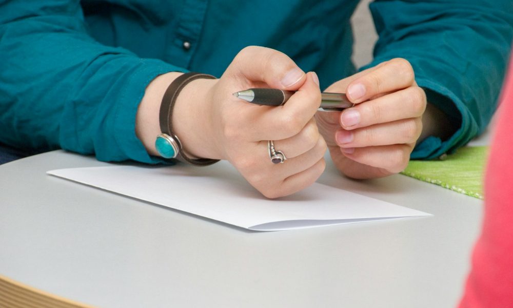 a person sitting at a table writing on a piece of paper