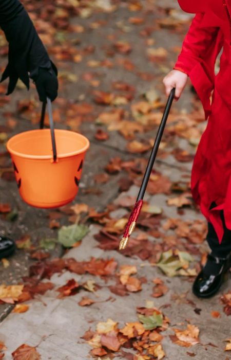 Two children in costumes holding Halloween buckets filled with candy.