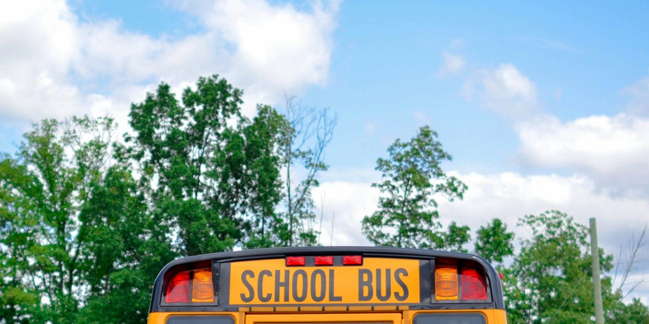 school bus near green trees under cloudy sky during daytime