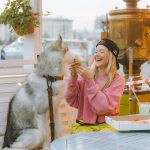 A joyful moment of a woman sharing pizza with her husky dog at an outdoor café.