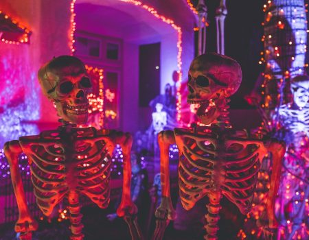 two skeleton near white concrete building with string lights at daytime