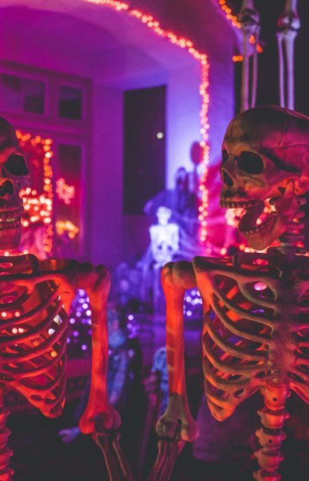 two skeleton near white concrete building with string lights at daytime