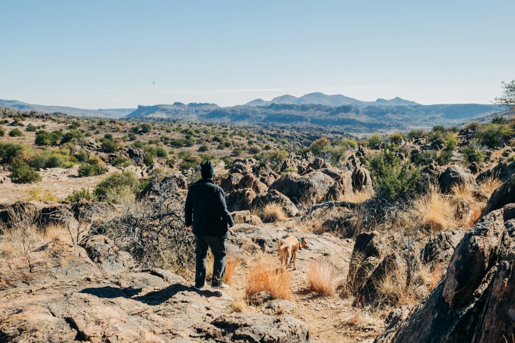 man in black jacket and black pants standing on brown rock during daytime