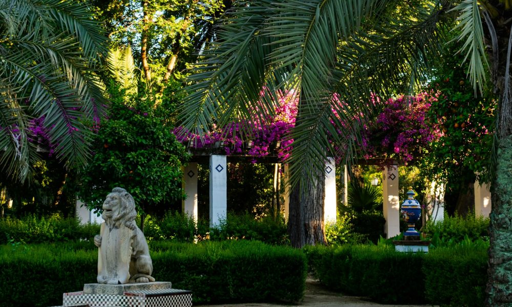 white statue of man and woman near green trees during daytime