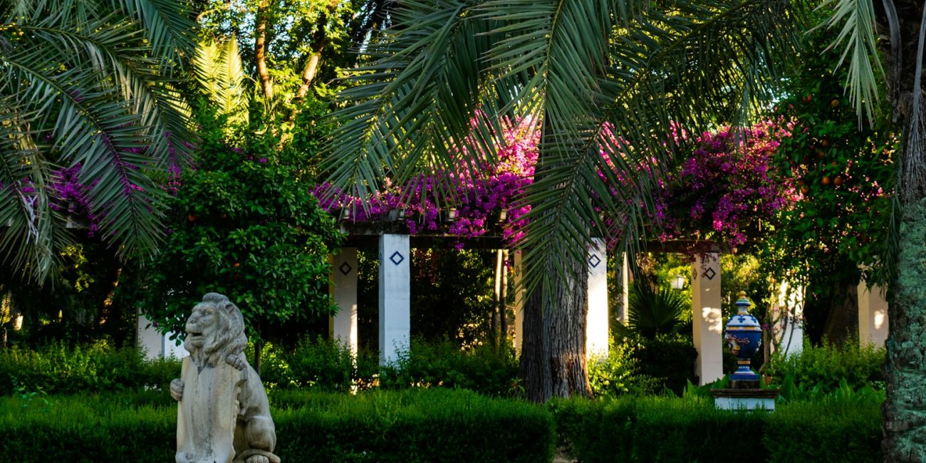 white statue of man and woman near green trees during daytime