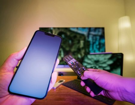 A person holding a cell phone and a remote control