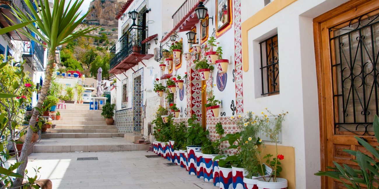 a narrow street lined with potted plants next to a building