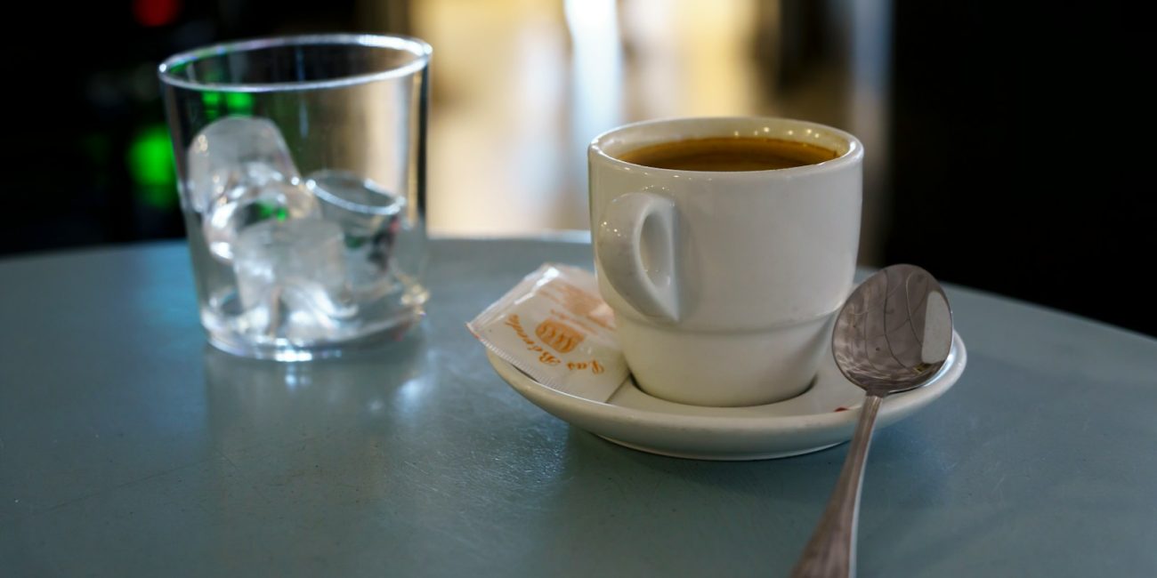 A cup of coffee and a spoon on a table