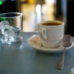 A cup of coffee and a spoon on a table