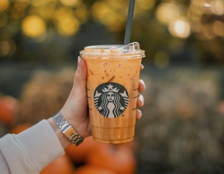 a person holding a starbucks drink with oranges in the background