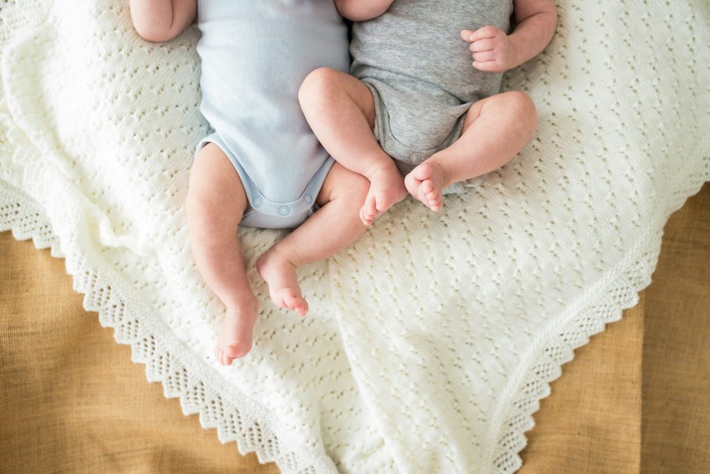 a couple of babies laying on top of a bed