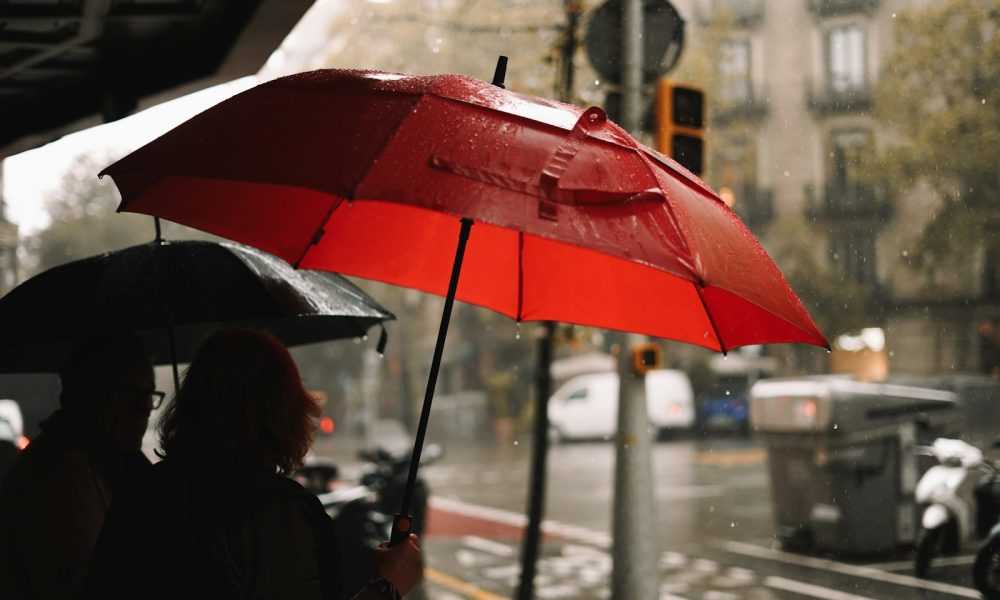 A person holding a red umbrella in the rain