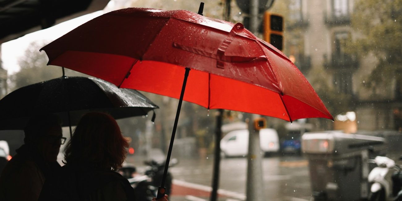 A person holding a red umbrella in the rain