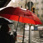 A person holding a red umbrella in the rain
