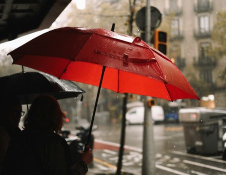 A person holding a red umbrella in the rain