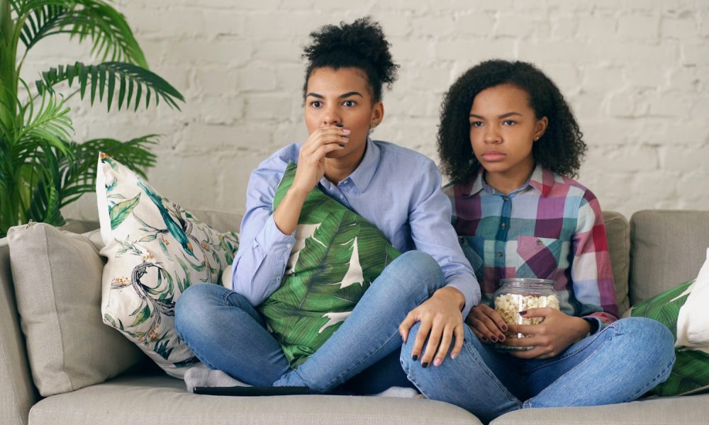 Two women watching television on a couch