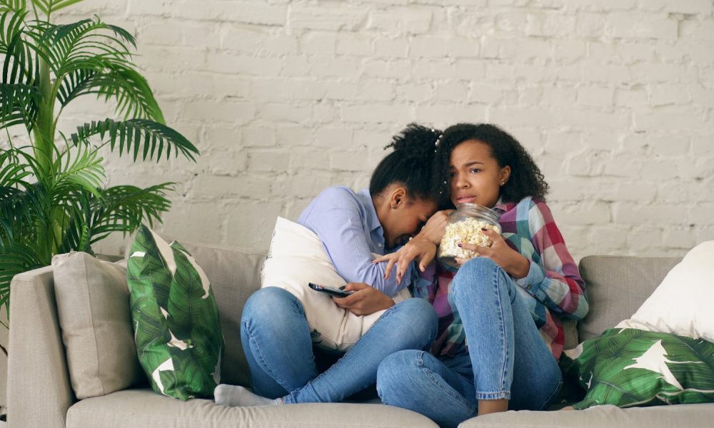 Two women watching TV and eating popcorn