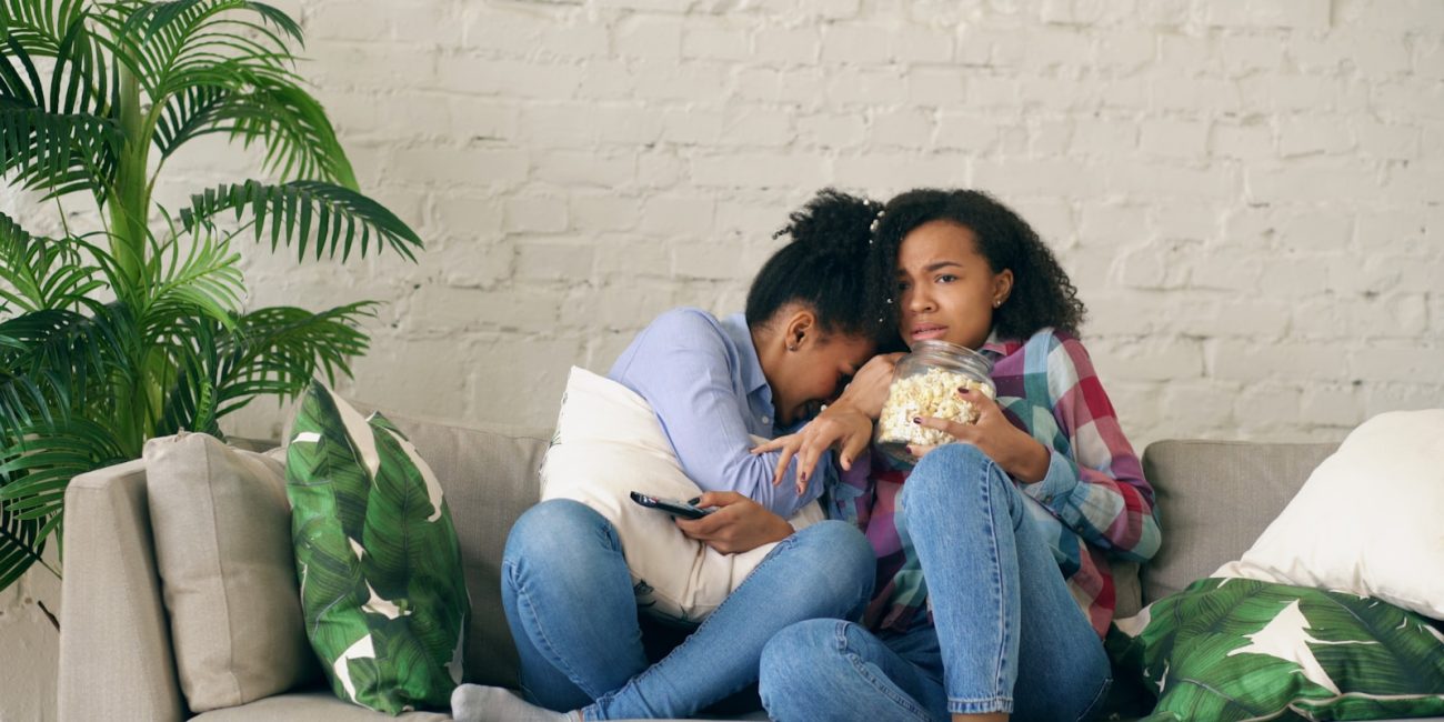 Two women watching TV and eating popcorn