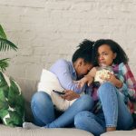 Two women watching TV and eating popcorn
