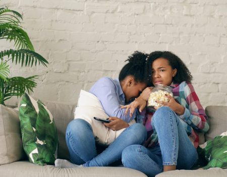 Two women watching TV and eating popcorn