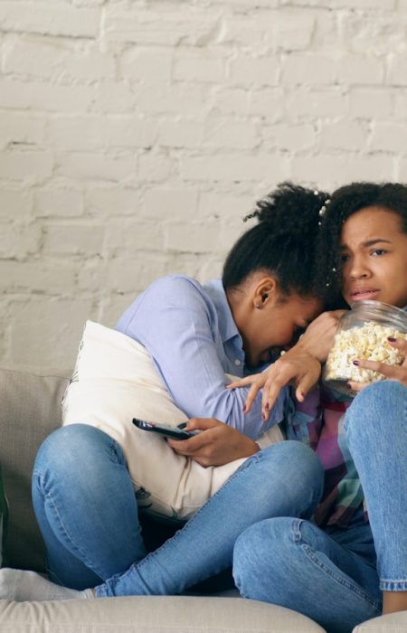 Two women watching TV and eating popcorn