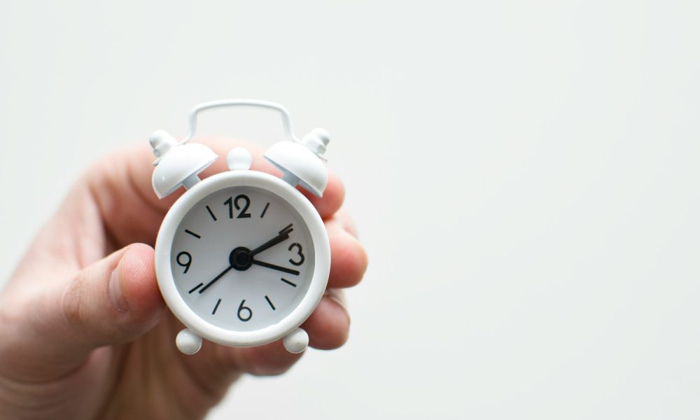 person holding white mini bell alarmclock