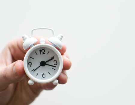 Don’t Forget to Fall Back! Spain’s October Clock Changing person holding white mini bell alarmclock