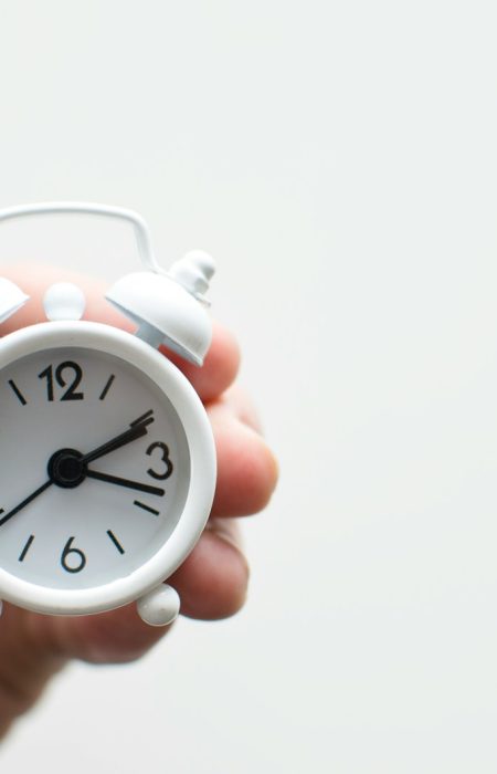 person holding white mini bell alarmclock