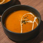 two bowls of soup on a wooden table