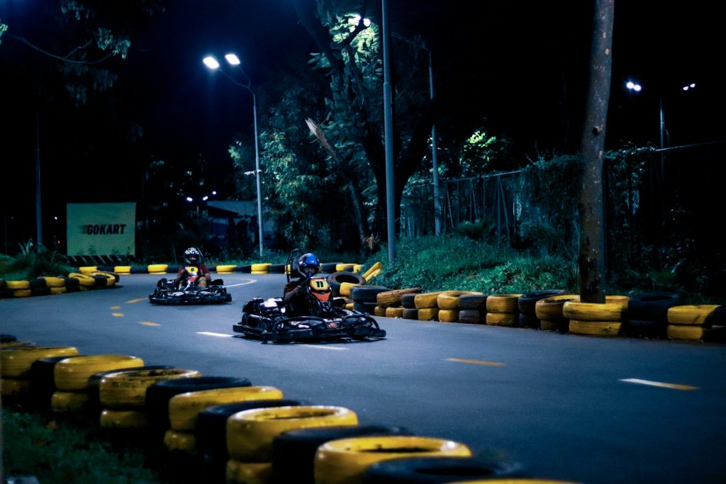 a group of people riding go karts on a road at night