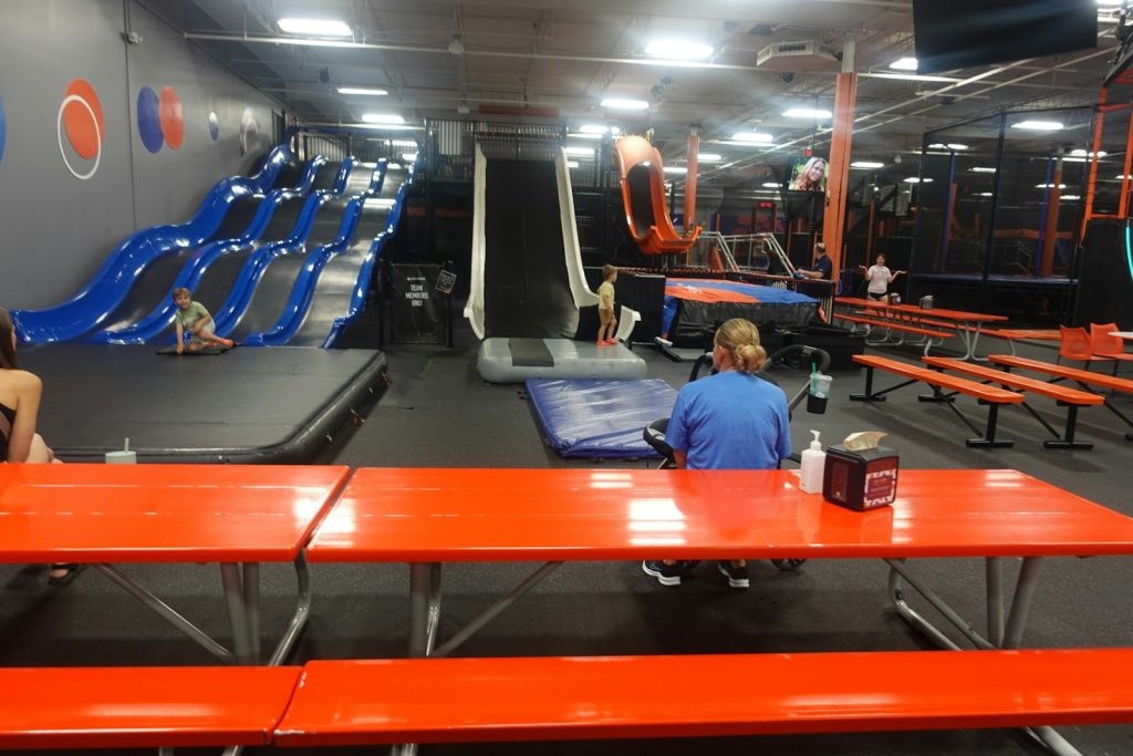 Indoor trampoline park with various activity stations.