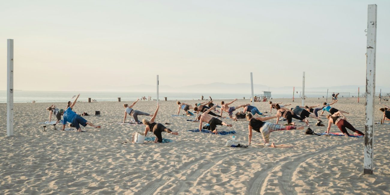 a group of people doing yoga on the beach