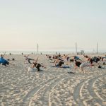 a group of people doing yoga on the beach