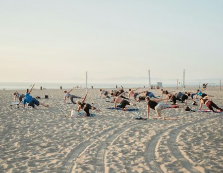 a group of people doing yoga on the beach