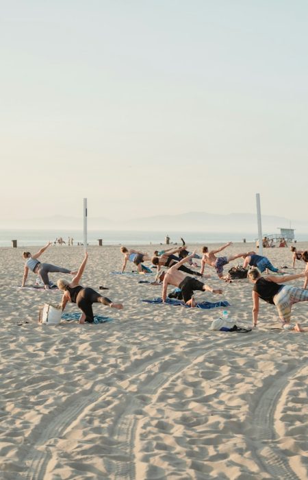 a group of people doing yoga on the beach